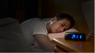 man having trouble sleeping looking at the clock
