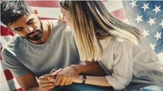 Couple holding hands in front of american flag